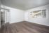 Bright, open living space with elegant wood flooring, large window for natural light, and a cozy entryway.