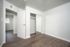 Bright and modern bedroom with sleek wood flooring, mirrored closet, and ample natural light.