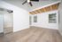 Bright and spacious room with elegant hardwood flooring, white walls, a mirrored closet, and a ceiling fan, offering a modern and inviting atmosphere.
