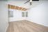 Bright, spacious room with wood-paneled ceiling, hardwood floors, and large windows, perfect for a modern living space.