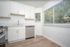 Bright modern kitchen with elegant white cabinetry, stainless steel appliances, and large windows offering abundant natural light.