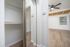 Modern apartment showcasing a sleek closet with mirrored doors, elegant wooden flooring, and a ceiling fan in a well-lit room.