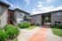 Charming apartment complex with modern architecture, lush landscaping, and inviting entryway under a bright blue sky.