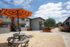 Charming apartment complex featuring modern balconies, vibrant landscaping, and a cozy outdoor seating area with a stylish umbrella.