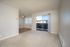 Bright and airy apartment living room featuring plush carpeting, large sliding glass doors leading to a balcony, and an adjacent dining area with ceiling fan, offering a cozy and inviting space.