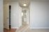 Bright apartment corridor showcasing freshly painted neutral walls, modern light fittings, and plush carpet, leading to a bathroom and closet space.