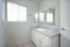Bright and modern bathroom featuring a sleek vanity, polished countertop, and large mirror under natural light.