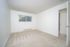 Bright and airy empty room with plush carpet and large window perfect for a cozy bedroom or serene office.