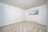 Bright and spacious room with fresh carpet, large window with vertical blinds, and clean white walls offering versatility for any decor.