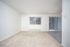 Bright and airy living room with fresh carpeting and large windows offering abundant natural light, enhancing the welcoming atmosphere.