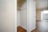 Inviting apartment interior showcasing a bright closet with wooden flooring, leading into a sunlit room with patio access.