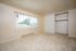 Bright and spacious bedroom with soft carpet flooring, large window letting in natural sunlight, and a roomy closet with sliding doors.