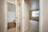 Inviting apartment hallway featuring a sleek bathroom with wood flooring and a bright bedroom with large windows, ready for personalization.