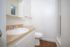 Bright and modern bathroom featuring elegant light wood accents, a sleek countertop, and a large mirror.