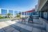 Bright rooftop terrace with modern seating and lush greenery, perfect for relaxation under clear blue skies.
