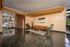 Elegant apartment lobby featuring a modern tan sofa, green velvet chairs, and stylish artwork, with glossy flooring and natural lighting.