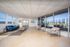 Bright and spacious living area with large windows, stylish seating, and access to a scenic outdoor patio.