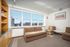 Bright and cozy living room with plush seating, large windows offering stunning city views, and elegant wall art.