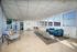 Bright and inviting lounge area with modern seating, a cozy blue sofa, and abundant natural light from large windows.