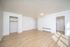Bright and spacious living area featuring modern light wood flooring, pristine white walls, and ample natural light.