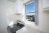 Bright kitchen nook with sleek modern stove, marble countertop, and a stunning city view from the window.