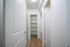 Bright hallway featuring elegant white doors and spacious built-in shelving, complemented by warm wood flooring.