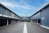 Charming apartment complex with modern blue facade, featuring an open walkway and covered parking, under a bright blue sky.