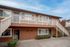 Charming two-story apartment building with a welcoming exterior and private stairway access, surrounded by lush greenery.