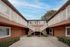 Charming two-story apartment complex with inviting staircases and vibrant greenery under a bright blue sky.