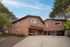 Charming two-story apartment building with a terracotta exterior, nestled among lush trees, featuring covered parking.