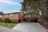 Charming two-story apartment building with covered parking, lush green landscaping, and a welcoming driveway.