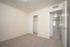 Bright, neutral-toned bedroom with plush carpeting and a spacious closet, opening into a welcoming hallway.