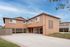 Charming two-story apartment with striking terracotta exterior, covered parking, and lush landscaping, ideal for modern living.