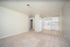 Contemporary apartment with an open layout, featuring a cozy carpeted living area and a bright kitchen with modern white cabinets and appliances.
