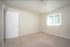 Bright, spacious bedroom with plush carpeting and a sunlit window offering a serene atmosphere.