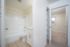 Bright apartment interior showcasing a modern bathroom with a clean white bathtub and sleek fixtures adjacent to a cozy carpeted bedroom.