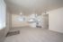 Bright and spacious open-plan living area with plush carpeting, modern kitchen, and ample natural light.