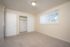 Bright, airy bedroom with plush carpet, ample closet space, and a large window with vertical blinds.