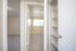 Bright apartment hallway with carpeted rooms, ample natural light, and modern shelving.