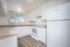 Bright and airy kitchen featuring modern white cabinetry, sleek countertops, and a large window with a tree view.