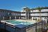 Charming apartment complex featuring modern balconies and a sparkling outdoor pool, surrounded by lush palm trees.