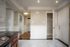 Bright and elegant apartment interior with modern kitchen featuring sleek countertops, open closet space, and crown molding accents.