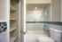 Elegant bathroom featuring a sleek shower-tub combination with modern tile design, complemented by built-in shelving for stylish storage options.