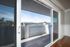 Elegant apartment balcony with picturesque views of lush hills and clear skies, framed by sleek sliding glass doors.