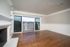 Bright living room with elegant fireplace, hardwood floors, and large sliding doors opening to a scenic balcony view.