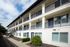 Charming multi-level apartment building with elegant balconies and lush greenery, offering modern living spaces.