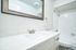 Bright and modern bathroom with a sleek vanity, elegant white countertop, and a full-size bathtub.