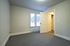 Bright and cozy bedroom with sleek carpeting, open door leading to a hallway, and natural light streaming through the window.