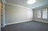 Bright and spacious room with modern carpeting, sleek crown molding, and large windows for natural light.