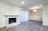 Elegant living area with modern fireplace, sleek wood flooring, and a large window with vertical blinds, offering a serene and inviting atmosphere.
